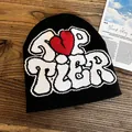 Detail of black knit beanie with TOP TIER jacquard text and red broken heart on wood - One Size / Black