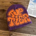 Detail of purple knitted beanie with bold orange TOP TIER lettering on wood background - One Size / Purple