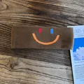 Detailed knit texture of brown athletic headband with embroidered colorful smiley face - Coffee