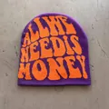 Detail view of purple knitted beanie with orange jacquard lettering flat lay on ground - One Size / Purple With Orange Letters