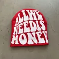 Detailed close-up of red knit beanie with white jacquard lettering on cement ground - One Size / Red