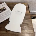Detail of soft white knitted balaclava with warm thick texture on wooden surface - White