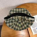 Detail view of green plaid ivy cap with metal buckle and leather strap on wood - Adjustable / Green