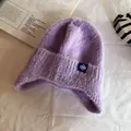 Detail of purple knit ear-flap hat with soft fuzzy texture and snowflake patch - One Size / Purple
