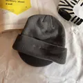 Détail du bonnet en maille gris foncé avec broderie Studious sur tissu blanc pur - Gris