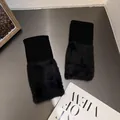 Detailansicht der schwarzen Strickhandschuhe mit dickem Kunstpelzbesatz auf dem Tisch - Schwarz