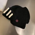 Detail of black knit knight helmet hat with cream stripes and functional red button - M (55-59cm) / Black