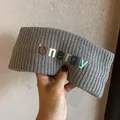 Gros plan d'un bandeau en maille grise avec lettres energy 3D colorées tenu à la main - Gris