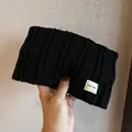 Detail of black ribbed knit headband showing thick texture and a white logo label - Black