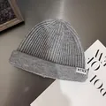 Detail of grey ribbed knit beanie featuring white NTRX letter label on textured surface - M / Gray