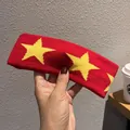 Detailed shot of a red knitted headband with yellow star patterns in hand - Red