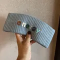 Détail d'un bandeau en maille grise avec lettres energy colorées en 3D et texture côtelée - Bleu