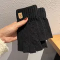 Detailed shot of black knitted fingerless gloves with a deer leather patch and ribbed cuffs - One Size / Black