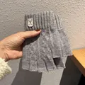 Close-up of grey knitted fingerless gloves with a vintage deer logo leather patch - One Size / Light Gray