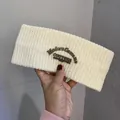 Detail of cream white knitted headband with a brown leather patch showing the logo - Off White