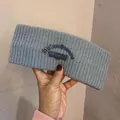 Macro detail of grey knitted headband with navy blue embroidered fashion label - Blue