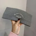 Detail of grey knitted wide headband with 3D embroidery showing premium winter texture - Gray