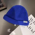 Detail of royal blue ribbed knit beanie with white NTRX letter label on grey metallic texture - M / Sapphire Blue