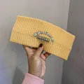 Detail of yellow chunky knit headband featuring black woven label with white text - Light Yellow