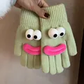 Detail of green knitted gloves featuring funny cartoon eyes and pink plush lips - Light Green