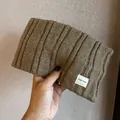 Detailed view of coffee brown knit headband with rib texture and white logo label - Khaki