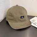 Detail view of khaki short brim canvas cap with mountain peak logo on wooden surface - Adjustable / Light Coffee