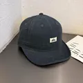 Dettaglio del cappello vintage in tela a tesa corta con etichetta su un tavolo di legno - Regolabile / Blu navy