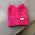 Details einer rosaroten Strickmütze mit Katzenohren aus flauschigem Webpelz und Etikett - Fuchsia