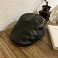 Detalle de la gorra vintage de cuero negro sobre un escritorio de madera rústica - Talla Única (55-58) / Negro