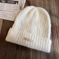 Détail du bonnet en maille crème avec texture pelucheuse et étiquette INSTITUTE - Taille unique (55-60cm) / Blanc