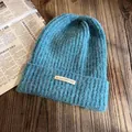 Gros plan du bonnet en tricot côtelé bleu avec étiquette sur une table en bois - Taille unique (55-60cm) / Bleu sarcelle
