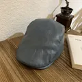 Primer plano de una gorra vintage de cuero gris sobre un escritorio de madera rústico - Talla Única (55-58) / Gris Azulado