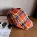 Détail d'une casquette plate à carreaux colorés posée sur un bureau en bois avec un livre - M / Orange