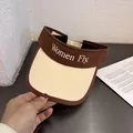 Detailed view of the canvas visor hat featuring embroidered Women Fly letters and brown trim - Kids (46-52cm) / Coffee