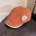Detail of vintage terracotta newsboy cap with white stitching and embroidered side patch - M (55-59cm) / Orange
