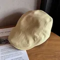 Gros plan détaillé d'une casquette plate en tricot beige sur une surface en bois chic - Taille unique / Kaki