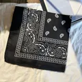 Bandana noir à motif cachemire blanc posé sur un tissu de fond texturé blanc - Noir