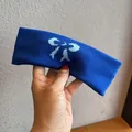 Detail of a navy blue knitted headband featuring a light blue bow pattern and soft texture - Sapphire Blue