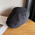 Casquette gavroche vintage noire en sergé posée sur un bureau en bois rustique - Taille unique / Noir