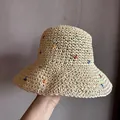Dettaglio di un cappello di paglia intrecciata con motivi ricamati colorati su trama beige - M (56-58cm) / Beige