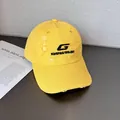 Dettaglio del cappellino giallo con effetto invecchiato, ricamo nero e dettagli strappati - Regolabile / Giallo