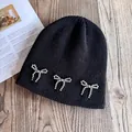 Detailed close-up of a black knit beanie featuring silver bead bow-knot decorations - M / Black