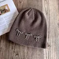 Détail du bonnet en maille marron foncé orné de nœuds en perles argentées sur bois - M(54-58cm) / Café