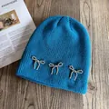 Detailed texture of bright blue ribbed knit hat with three silver beaded bow decorations - M / Teal