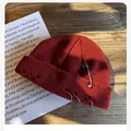 Burgundy distressed knit beanie featuring silver rings and safety pin on dark wood - M (54-59cm) / Burgundy