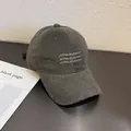 Détail d'une casquette de baseball en velours gris avec broderie sur un bureau - Réglable / Gris