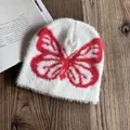 Nahaufnahme einer weißen Plüschmütze mit rotem Schmetterlingsmuster und weicher Textur - M (54-58cm) / Weiß