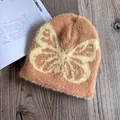 Details einer weichen Strickmütze aus Nerzimitat mit gelbem Schmetterling auf Orange - M (54-58cm) / Erdgelb