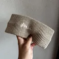 Detailed view of khaki knitted elastic headband with white embroidered letter M accent - Mocha
