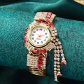 Dettaglio macro di un orologio dorato da donna con strass incastonati e ciondoli a nappa - Strass Rosa